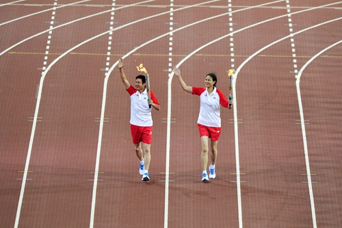 第一棒火炬手陈忠和与侯玉珠跑进了体育场