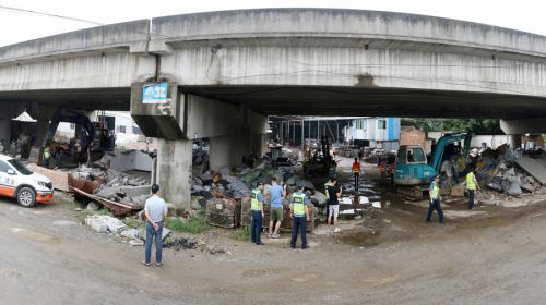 闽侯青口的高速路桥下堆满杂物，执法人员正在清理